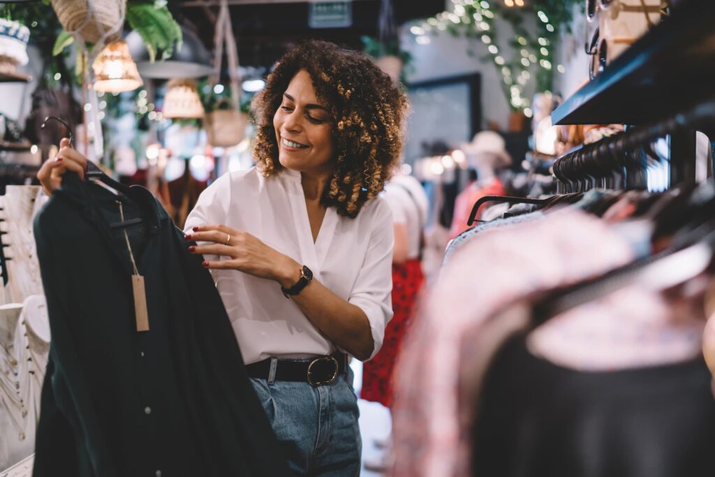 Market research -Women holding up a dark shirt on a hanger in a clothing store