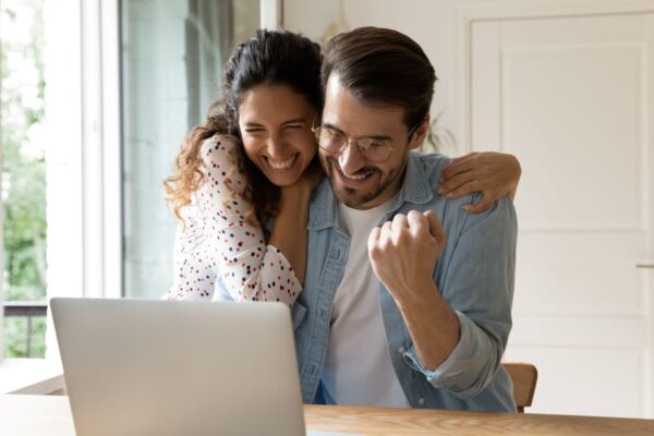 Allwyn - Couple celebrating in front of laptop after winning the lottery
