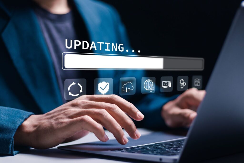 Image of an office worker typing on laptop and updating software. A progress bar is shown superimposed above the keyboard.