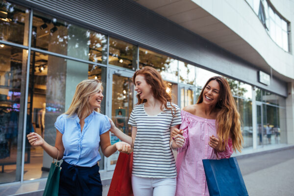 Centre Growth Model - Three women shopping together holding shopping bags in front of a store